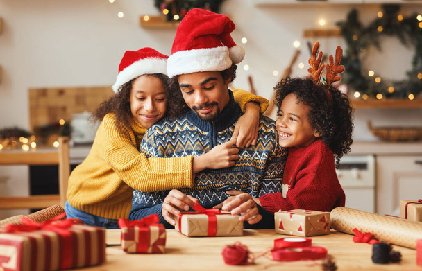 Happy african american family father and kids daughter and son pack Christmas gifts - Photo, Image