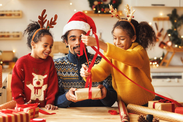 Χαρούμενη αφροαμερικάνικη οικογένεια πατέρας και παιδιά κόρη και γιος πακέτο χριστουγεννιάτικα δώρα - Φωτογραφία, εικόνα