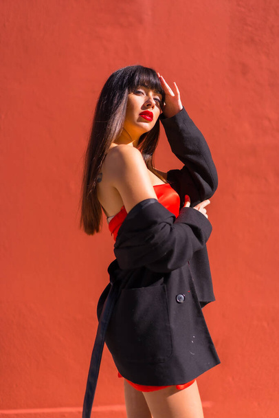 Brunette model posed in a portrait on a red background, red dress, provocative girl - Zdjęcie, obraz