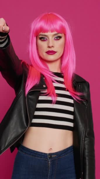 Függőleges videó: Menő punk nő mutatja hüvelykujját lefelé jel stúdióban, mutatja rosszallás és csalódás. Divatos elegáns lány bőr kabát csinál nem szereti a rossz szimbólum, negatív egyet nem értés gesztus. - Felvétel, videó