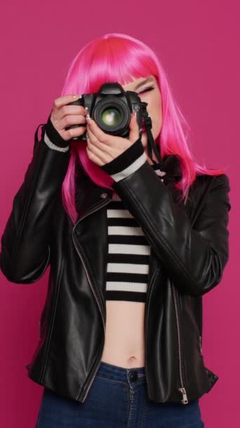 Κάθετο βίντεο: Νεαρή όμορφη γυναίκα που εργάζεται με την κάμερα dslr ως φωτογράφος, χρησιμοποιώντας τη συσκευή για να τραβήξετε φωτογραφίες και να διασκεδάσετε. Αρκετά χαρούμενος άνθρωπος είναι ανέμελη και λήψη εικόνων, φωτογραφία - Πλάνα, βίντεο