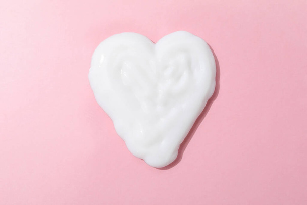 Heart made of cream on pink background - Foto, Bild