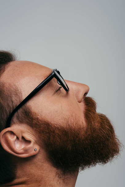 Oldalnézet szakállas férfi szemüvegben csukott szemmel elszigetelt szürke  - Fotó, kép