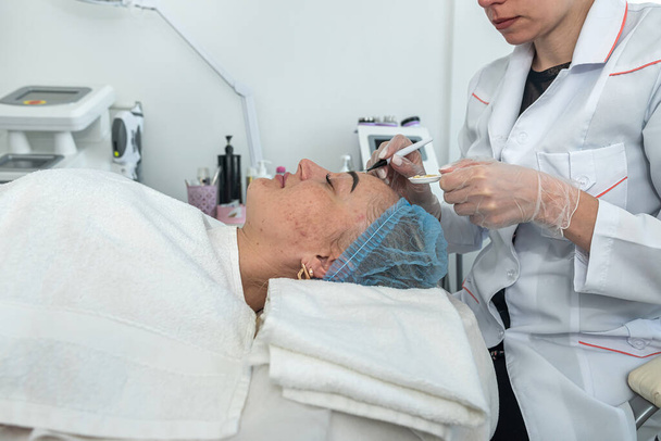 косметолог наносить маску на обличчя пацієнта косметичними пензлями, лежачи. косметолог. косметичні процедури
 - Фото, зображення