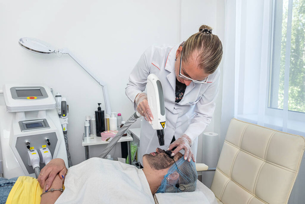 Imagem de close-up de um dermatologista aplicando uma máscara de barro com uma escova sintética no rosto de um cliente. dermatologista cosmetologia problemas de pele - Foto, Imagem