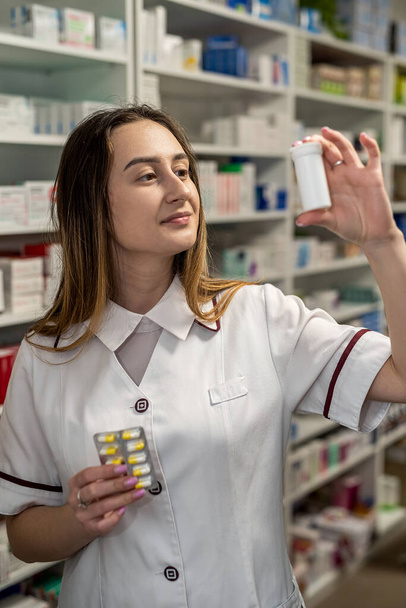 Un farmacéutico con una bata blanca muestra las pastillas disponibles a la cámara. Concepto farmacéutico. Farmacia para la salud - Foto, imagen