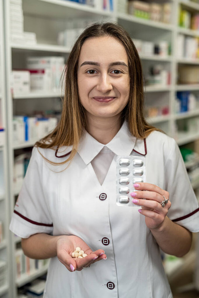 Un farmacéutico con una bata blanca muestra las pastillas disponibles a la cámara. Concepto farmacéutico. Farmacia para la salud - Foto, imagen