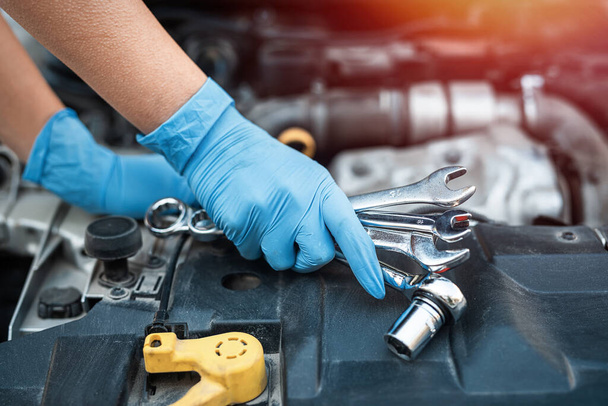 Männliche Mechaniker helfen Frau, das Problem der Autopanne zu lösen. Er hebt die Motorhaube des Autos an, um das beschädigte Teil zu reparieren. Menschenhände aus nächster Nähe - Foto, Bild