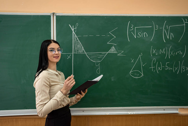 portrait of female student in the classroom near chalkboard. education concept  - Photo, Image