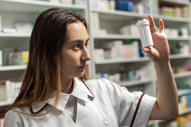 Una farmacéutica revisa los estantes en busca de medicamentos. Concepto farmacia y farmacéutico - Foto, Imagen
