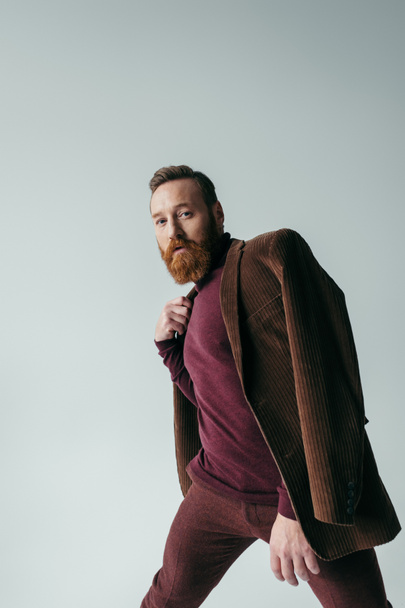 bearded man in turtleneck and brown blazer looking at camera isolated on grey  - Photo, Image