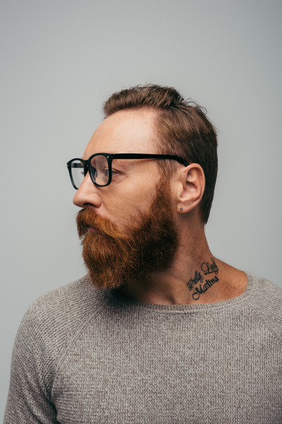 bearded and tattooed man in long sleeve and eyeglasses isolated on grey  - Photo, Image