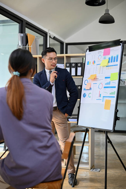 Toplantıda profesyonel ve akıllı Asyalı işadamı veya erkek finans danışmanı, mali sorunlar için bir çözüm planı düşünerek toplantıda sunum yapıyor. - Fotoğraf, Görsel