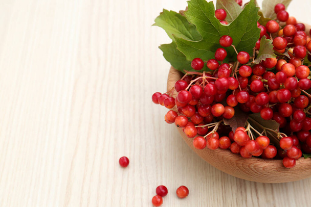 Bowl with tasty viburnum berries on white wooden table. Space for text - Foto, imagen