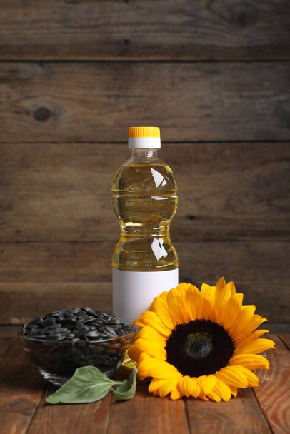 Sunflower cooking oil, seeds and yellow flower on wooden table - Foto, immagini