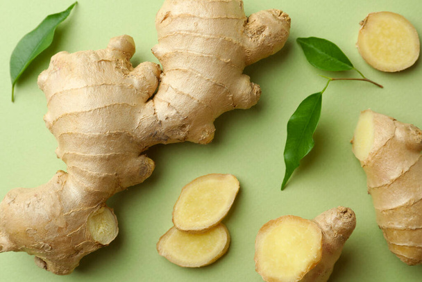 Fresh ginger with leaves on light pale green background, flat lay - 写真・画像