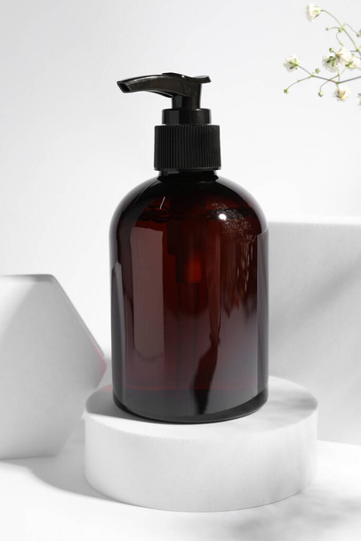 Bottle of shampoo on podium against white background - Photo, image