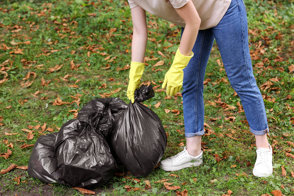 Woman holding plastic bags with garbage in park, closeup. - Foto, imagen