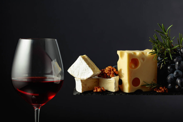 Siyah arka planda peynirli, cevizli, üzümlü ve biberiyeli kırmızı şarap.. - Fotoğraf, Görsel