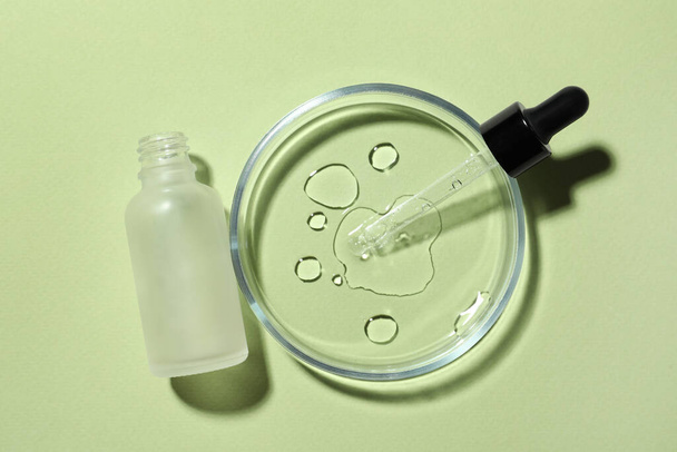 Petrischaal met pipet en fles op lichtgroene ondergrond, plat gelegd - Foto, afbeelding