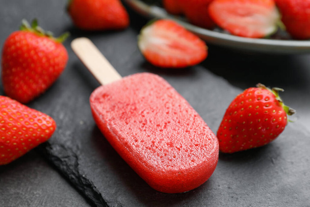 Tasty strawberry ice pop on dark table, closeup. Fruit popsicle - Zdjęcie, obraz