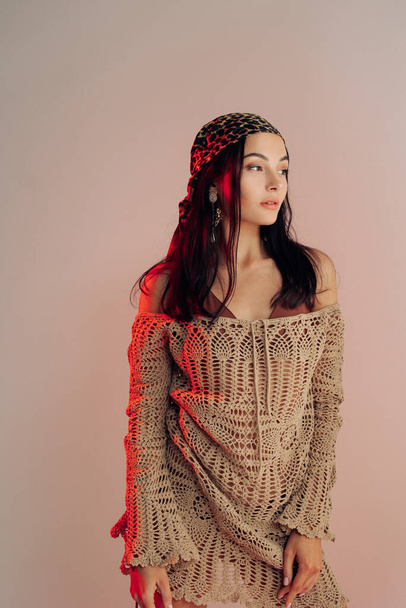 Young woman poses in knitted lacy dress and bandana with red backlight. - Foto, immagini