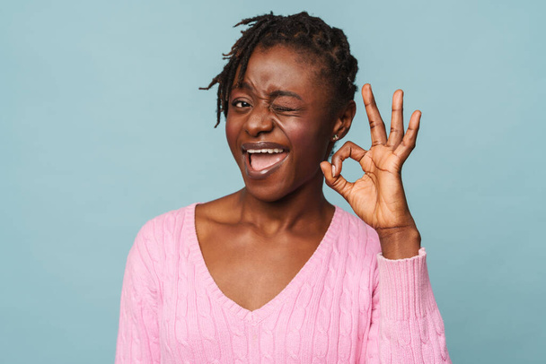 African american happy woman smiling and doing okay gesture isolated over blue background - Fotoğraf, Görsel