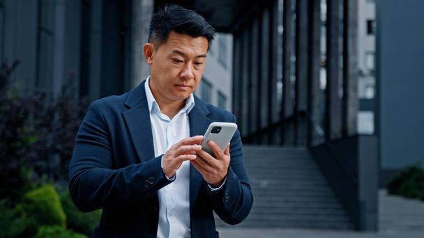 市内のアジア人実業家は携帯電話に問題がある。中年のCEO雇用主起業家屋外の携帯電話の感覚が壊れてミスエラーで動揺オンライン携帯電話の接続が失われました - 写真・画像