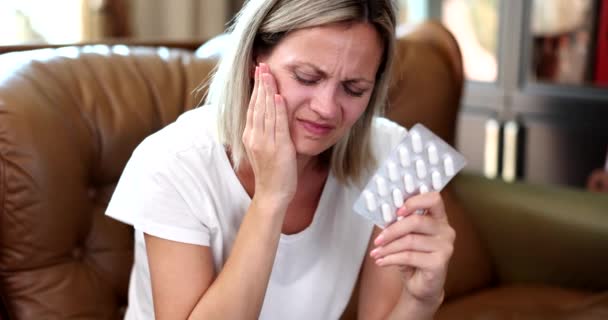Donna con forte mal di denti con pillole sul divano. Pillole per il mal di denti sono veloci ed efficaci - Filmati, video