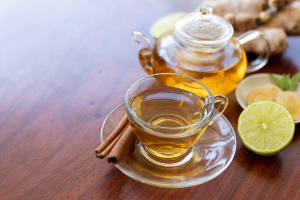 a cup of tea with ginger root, lime, cinnamon and teapot on white background. Health drink concept. - Foto, imagen