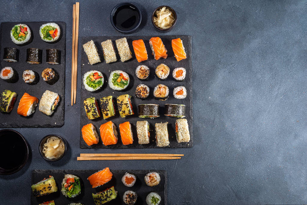 Sushi set on dark slate background, with soy sauce, ginger and chopsticks, copy space - Photo, Image