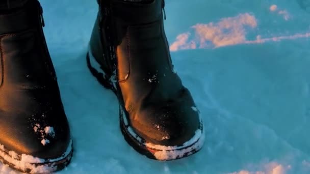 Egy fekete bőrcsizmás férfi télen megmozdítja a lábát. - Felvétel, videó