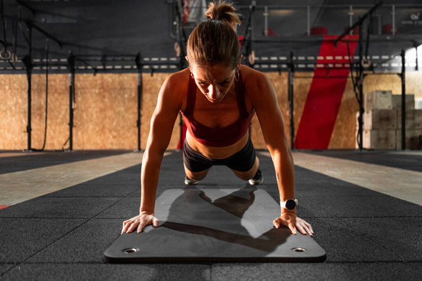 morena chica caucásica haciendo deportes acostado en una alfombra suave en un gimnasio - concepto de Crossfit - Foto, Imagen
