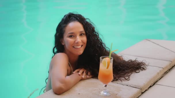 Соблазнительная сексуальная женщина латиноамериканская брюнетка в купальнике пьет коктейль в летнем бассейне красивая тысячелетняя туристка флиртует отдых со свежим соком на спа-курорте роскошного отеля - Кадры, видео