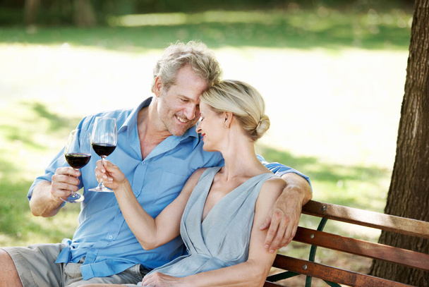 Condividere un momento affettuoso. Felice coppia matura brindare il loro amore con due bicchieri di vino mentre all'aperto - Foto, immagini