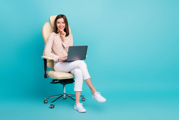 Full length photo size photo of businesswoman sitting chair touch chin using netbook positive smile empty space proposition isolated on blue color background. - Foto, Imagen