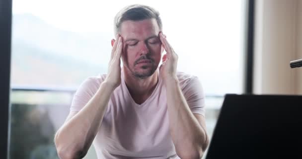Stressaantunut väsynyt mies, jolla on vakava kauhea päänsärky työskenneltyään kannettavan tietokoneen. Väsynyt uupunut freelancer kärsivät krooninen migreeni - Materiaali, video