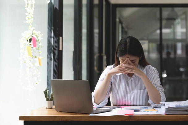 Aasian naiset ovat stressaantuneita työskennellessään kannettavan, Väsynyt aasialainen liikenainen päänsärky toimistossa, pahoinvointi työssä. - Valokuva, kuva