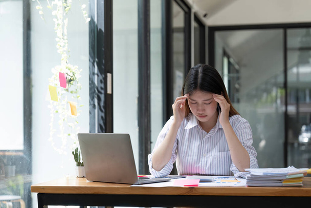 仕事でストレスを感じる、オフィスで頭痛の種と疲れてアジアのビジネス女性. - 写真・画像