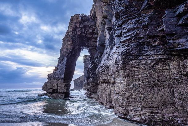 Природні рок-арки пляж Cathedrals, Playa de las catedrales at Ribadeo, Galicia, Spain. Знаменитий пляж в Північній Іспанії Атлантичний. Природна кам "яна арка на узбережжі Катедралів у припливі.. - Фото, зображення
