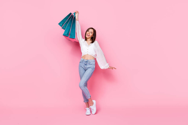Full length photo of positive stylish lady rejoice hand hold raise bag new trendy clothes empty space isolated pink color background. - Φωτογραφία, εικόνα