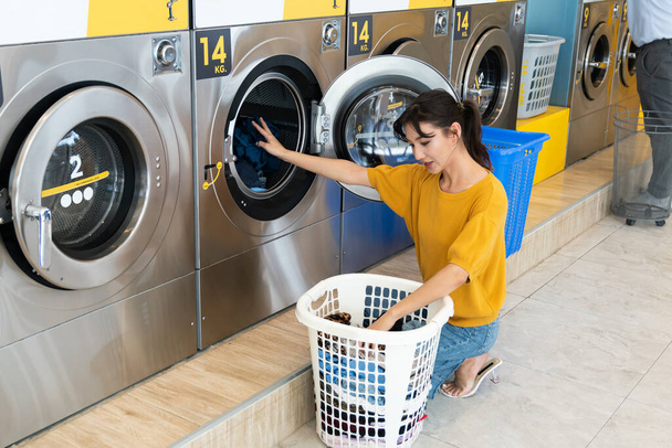 Asiaten benutzen eine Münzwaschmaschine im öffentlichen Raum, um ihre Tücher zu waschen. Konzept einer gewerblichen Selbstbedienungswasch- und Trocknungsmaschine in einem öffentlichen Raum. - Foto, Bild