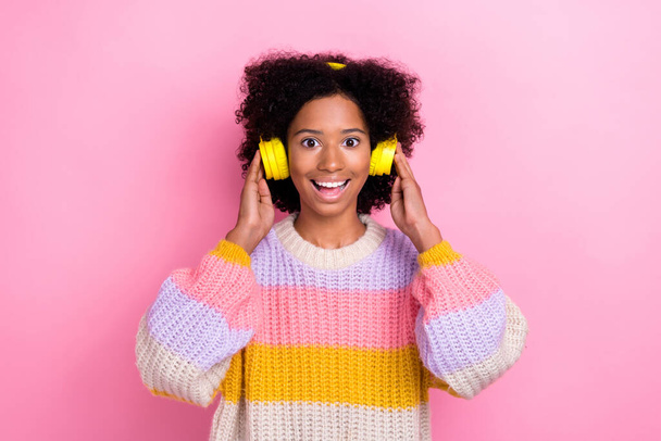 Photo of ecstatic overjoyed girl with perming coiffure dressed knit sweater hands touch headphones isolated on pink color background. - Fotoğraf, Görsel