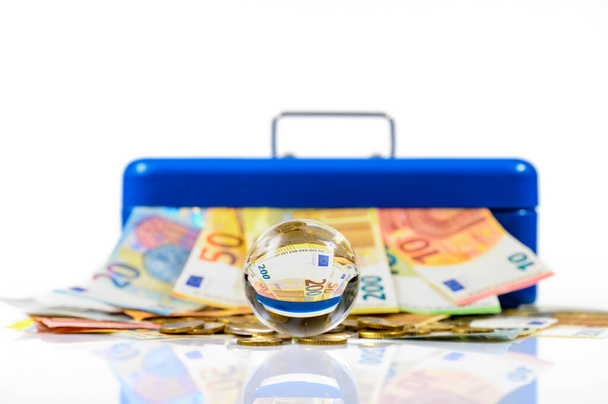 євро купюри і монети лежать на столі і стирчать з синьої касової коробки з відображенням у скляній кулі
 - Фото, зображення