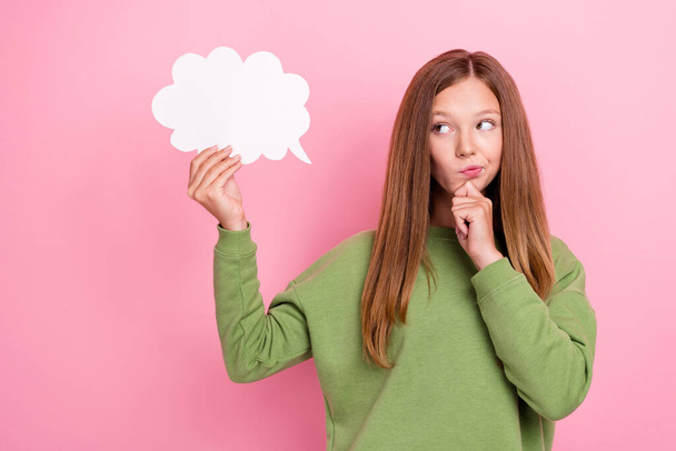 Photo of funny doubtful schoolgirl wear green sweatshirt looking mind cloud empty space arm chin isolated pink color background. - 写真・画像