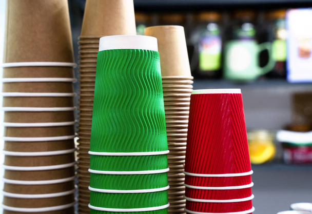 A stack of colorful disposable paper cups in a cafe. Paper cups from kraft paper for various drinks. Close-up. Selective focus. - Fotó, kép