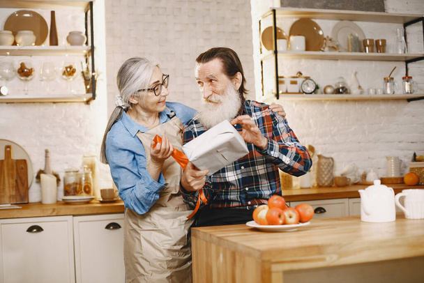 Age and people concept . Senior couple at home. Womangive gift for her husband. - 写真・画像