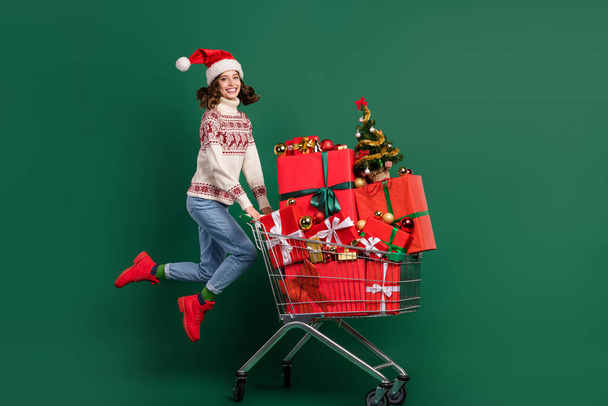 Full size photo of excited crazy girl jumping push market trolley pile stack giftbox isolated on green color background. - Fotoğraf, Görsel
