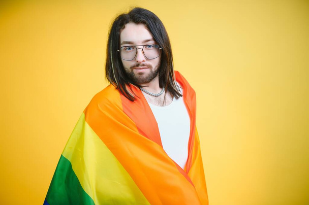 Gay man hold rainbow striped flag isolated on colored background studio portrait. People lifestyle fashion lgbtq concept. - Foto, afbeelding
