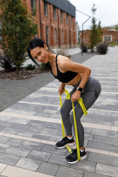 Fitness woman using a rubber expander band during workout exercise  - Photo, Image